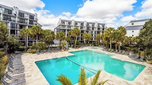 A hotel with a swimming pool, palm trees, and modern buildings.
