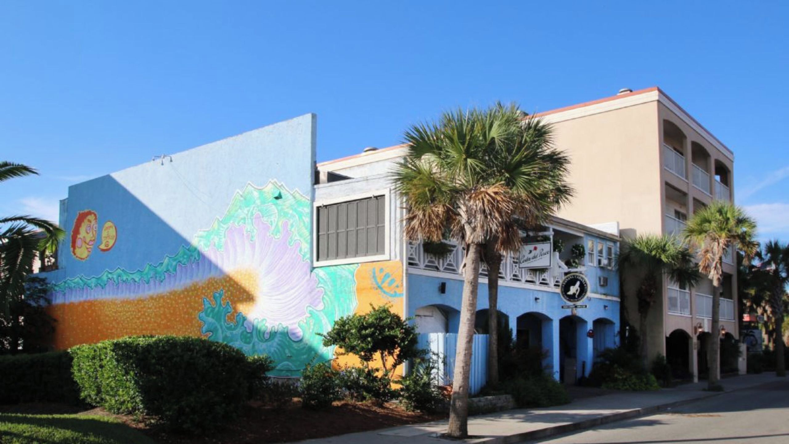 A building with a colorful mural, a palm tree, and a sign that reads 'Casa de Coral'.