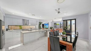 Una cocina moderna con una isla central, comedor con sillas y un televisor.