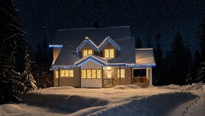 A house with a snow-covered landscape, a visible driveway, and a porch with a railing.