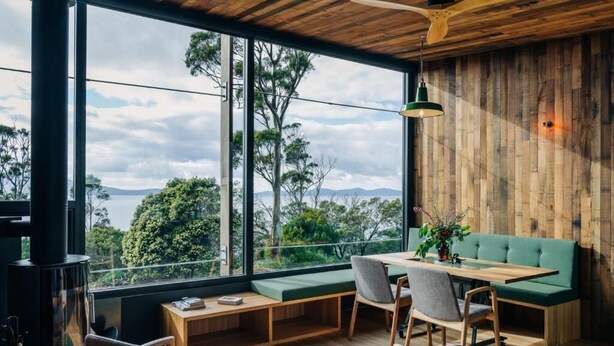 A modern interior with a large window, wooden ceiling, and a green sofa.
