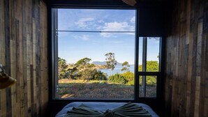 A room with a large window, a bed, and two chairs.