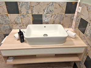 A bathroom with a rectangular sink, a faucet, a towel, and a soap dispenser. - Gasthaus zur Linde (Seevetal)