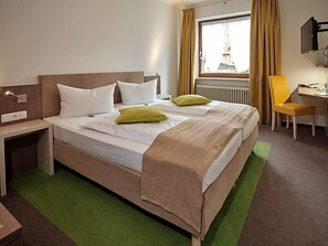 Una habitación de hotel con una cama, un escritorio, una silla y un televisor.