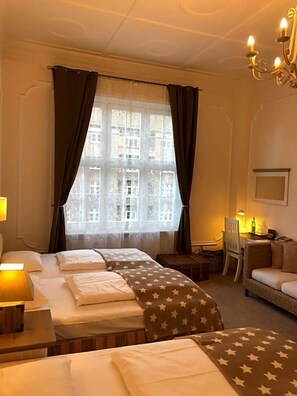 Et hotelværelse med to senge, et skrivebord, en stol og en sofa.