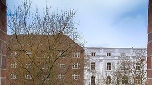 A balcony with two white chairs, a small round table with a wine bottle, and a view of buildings in the background. - Fresena (Hamburg)