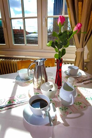 A table with a coffee setup, a vase with flowers, and a window with a view. - Fresena (Hamburg)