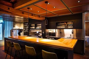 A bar area with a long counter, stools, and shelves with glasses and bottles. - Gasthaus Zum Trauben (Weinfelden)