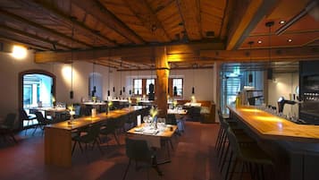 Ein geräumiges Restaurant mit hohen Decken, Holzbalken und einer langen Bar.