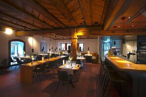 Un restaurante espacioso con techos altos, vigas de madera y una amplia zona de bar.