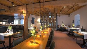 A restaurant with long wooden tables, hanging lights, and a rustic ceiling. - Gasthaus Zum Trauben (Weinfelden)