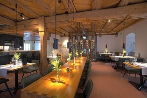 A restaurant with long wooden tables, hanging lights, and a rustic ceiling. - Gasthaus Zum Trauben (Weinfelden)