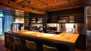 A bar area with a long wooden counter, bar stools, and a well-lit ceiling with recessed lighting. - Gasthaus Zum Trauben (Weinfelden)