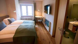 A hotel room with two beds, a desk, a chair, a TV, and a bathroom. - Gasthaus Zum Trauben (Weinfelden)