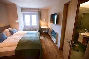 A hotel room with two beds, a desk, a chair, a TV, and a bathroom. - Gasthaus Zum Trauben (Weinfelden)