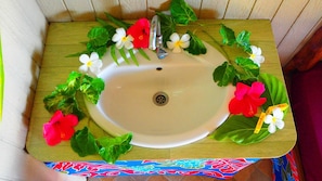 A bathroom sink with a white basin, a faucet, and decorative flowers and leaves.