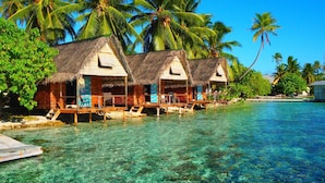 Overwater bungalows with thatched roofs, wooden decks, and clear blue water. - Tetamanu Village (Fakarava)