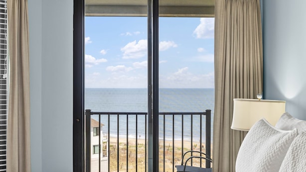 Habitación de hotel con un ventanal grande que ofrece vistas a la playa y al océano.