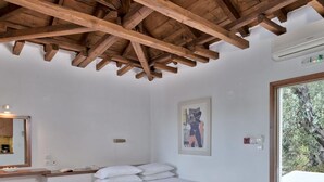 Ein Schlafzimmer mit Holzboden, einem Bett, einem Schreibtisch mit Stuhl, einem gerahmten Bild an der Wand und einem Fenster.