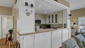 Una cucina con mobili bianchi, un forno a microonde e un lavello.
