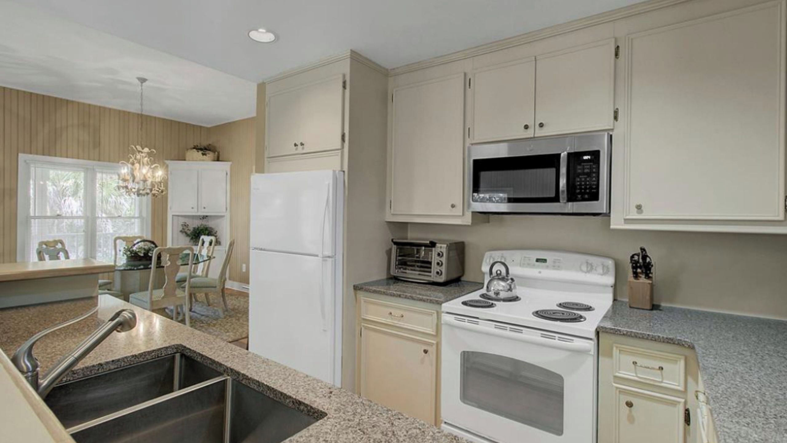 A kitchen with a white refrigerator, a microwave, a stove, and a sink.