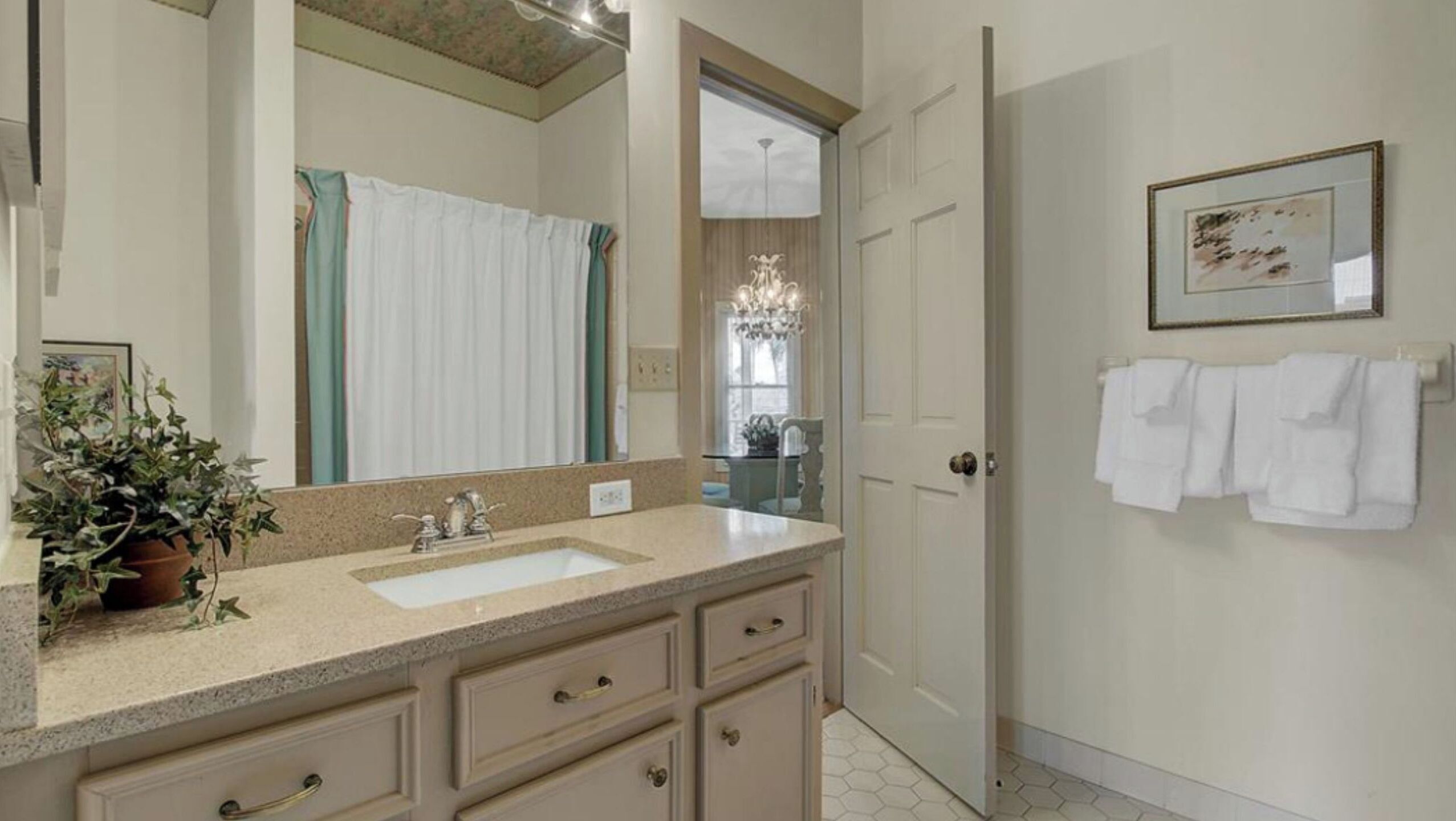 A bathroom with a sink, mirror, towel rack, and a potted plant.
