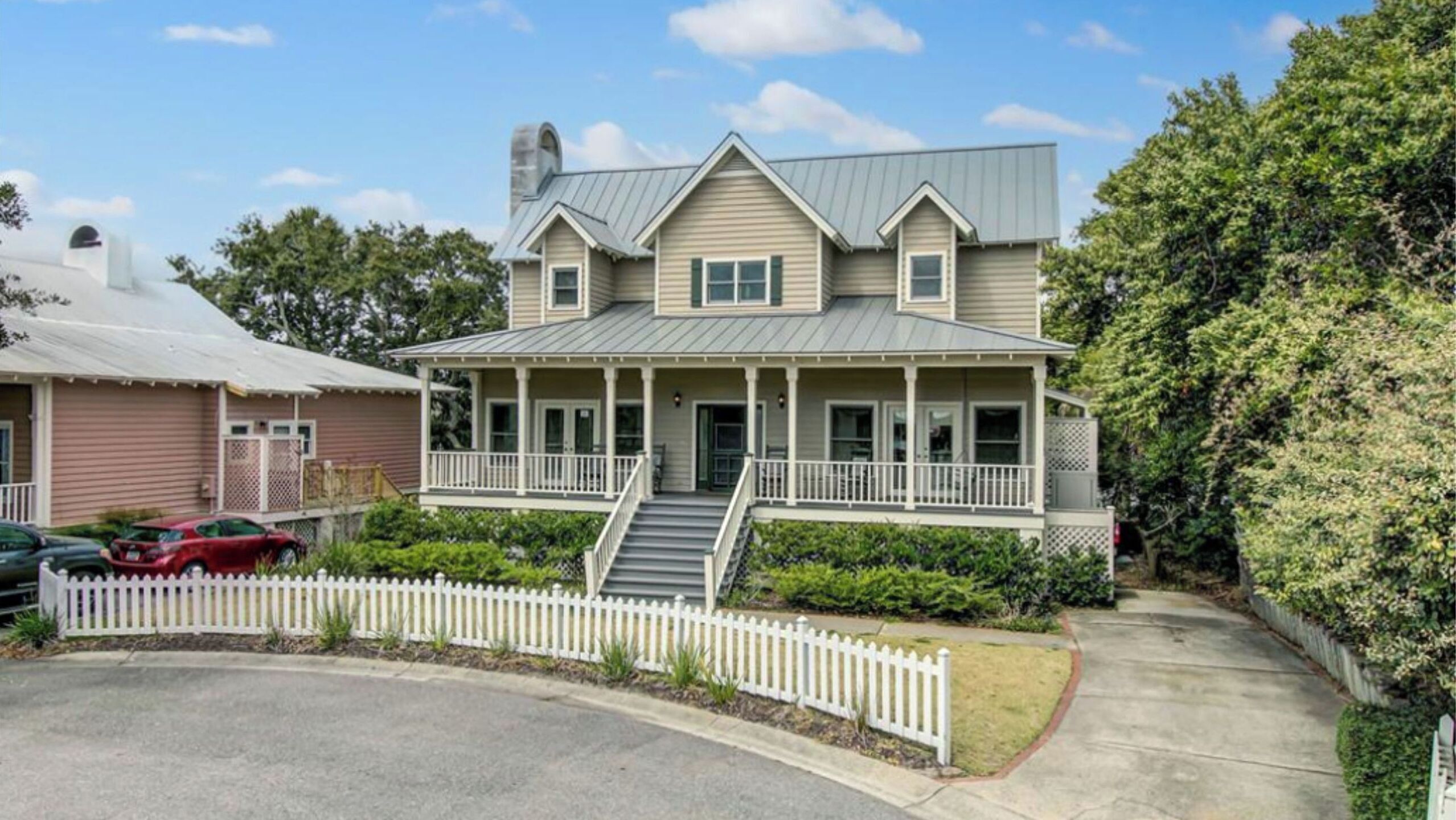 A two-story house with a porch, a chimney, and a white picket fence.