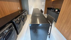 A modern kitchen with a central island, built-in appliances, and a dining area. - Bela Hospedagem - 105 Solaz Smart (João Pessoa)