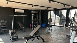 A gym with weightlifting equipment, a bench, and a treadmill. - Bela Hospedagem - 105 Solaz Smart (João Pessoa)