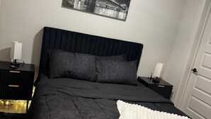 A bedroom with a large bed, two bedside tables, a wall-mounted picture, and a door.