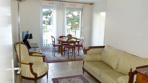A living room with a sofa, chairs, a dining table, and a TV. - Bouchardon (Paris)