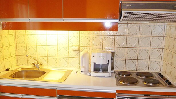 A kitchen with a sink, coffee maker, stove, and dishwasher. - Bouchardon (Paris)