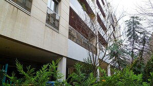 A multi-story building with balconies, a tree in the foreground, and a clear sky. - Bouchardon (Paris)