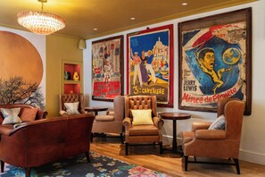 A lounge area with leather armchairs, a chandelier, and vintage posters on the wall. - Dukes Hotel (Bath)
