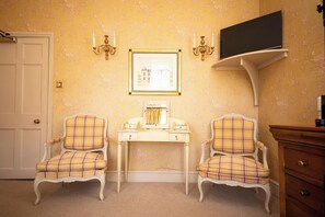 A room with two armchairs, a small table, a framed picture, a television, and a door. - Dukes Hotel (Bath)