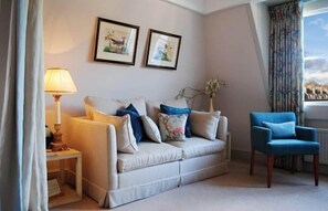 A living room with a sofa, a chair, a lamp, and two framed pictures on the wall. - Dukes Hotel (Bath)
