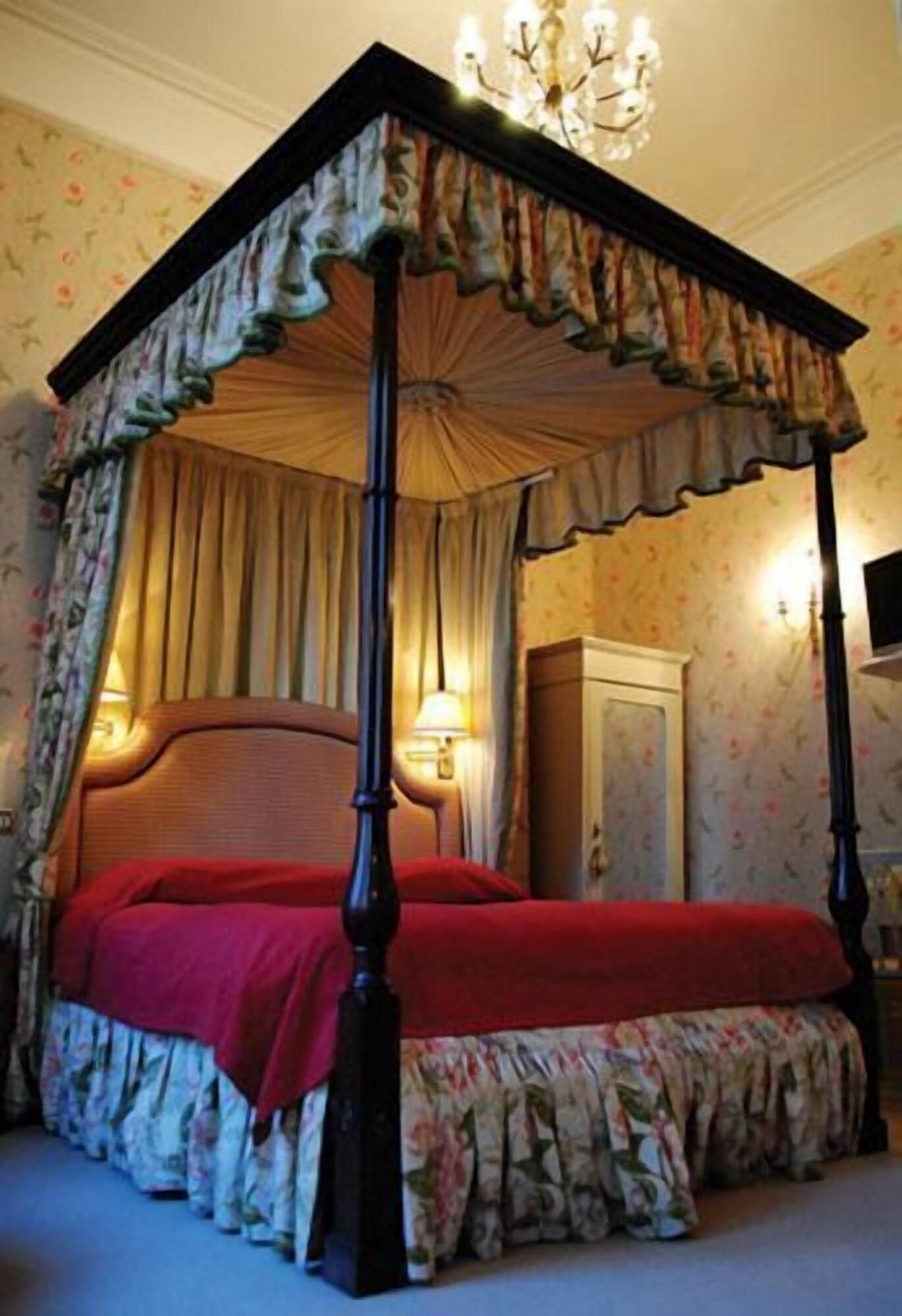 Un lit à baldaquin avec des poteaux aux quatre coins, une tête de lit en bois et une couvre-lit rouge.