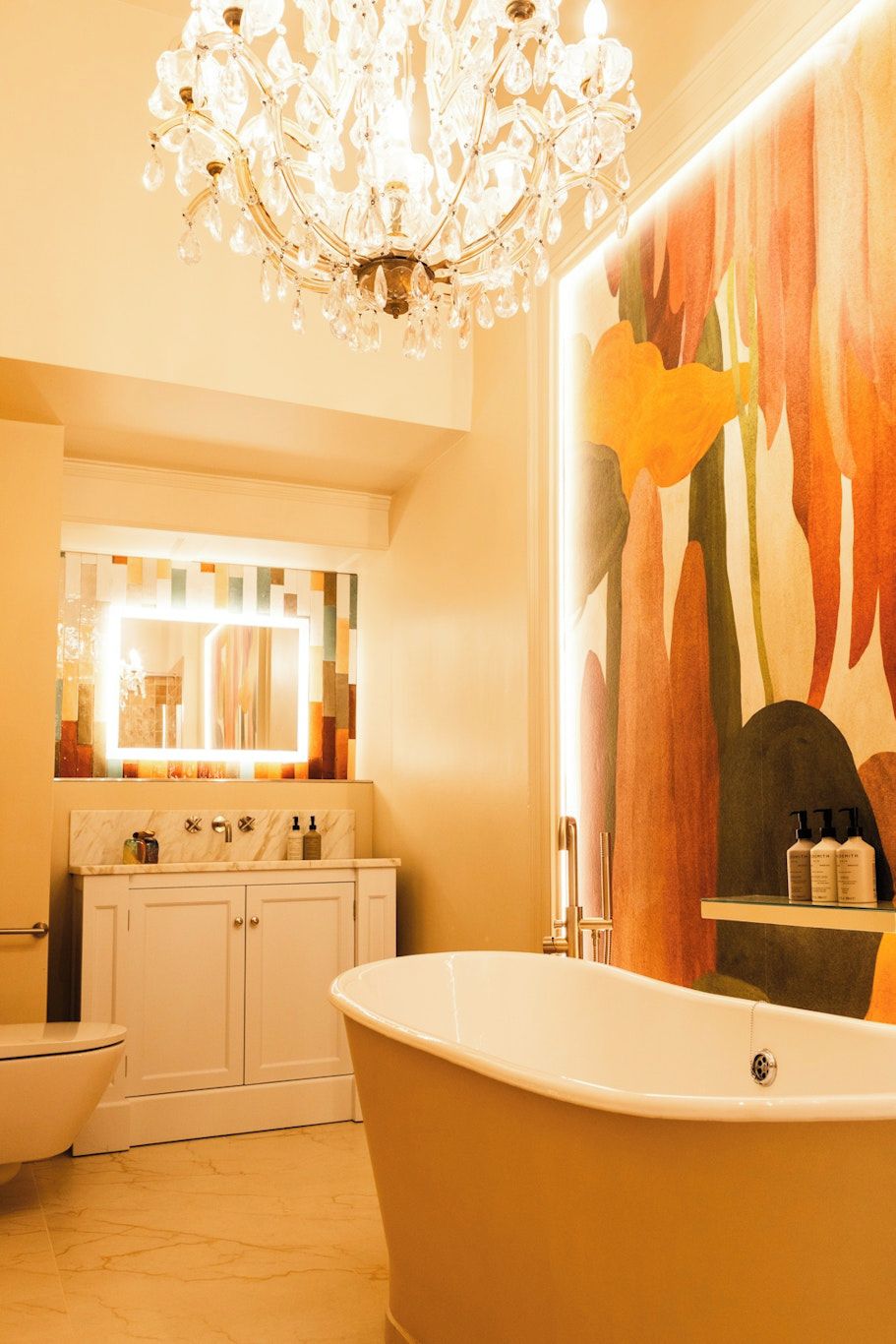 A bathroom with a freestanding bathtub, a large mirror, and a chandelier.