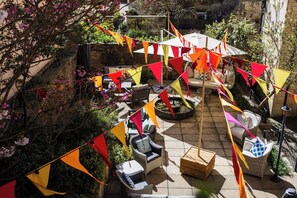 An outdoor patio with seating, a fountain, and colorful flags. - Dukes Hotel (Bath)