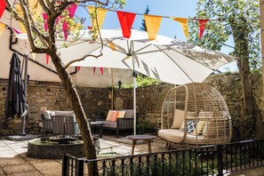 An outdoor seating area with a wicker chair, a round table, and a decorative umbrella. - Dukes Hotel (Bath)