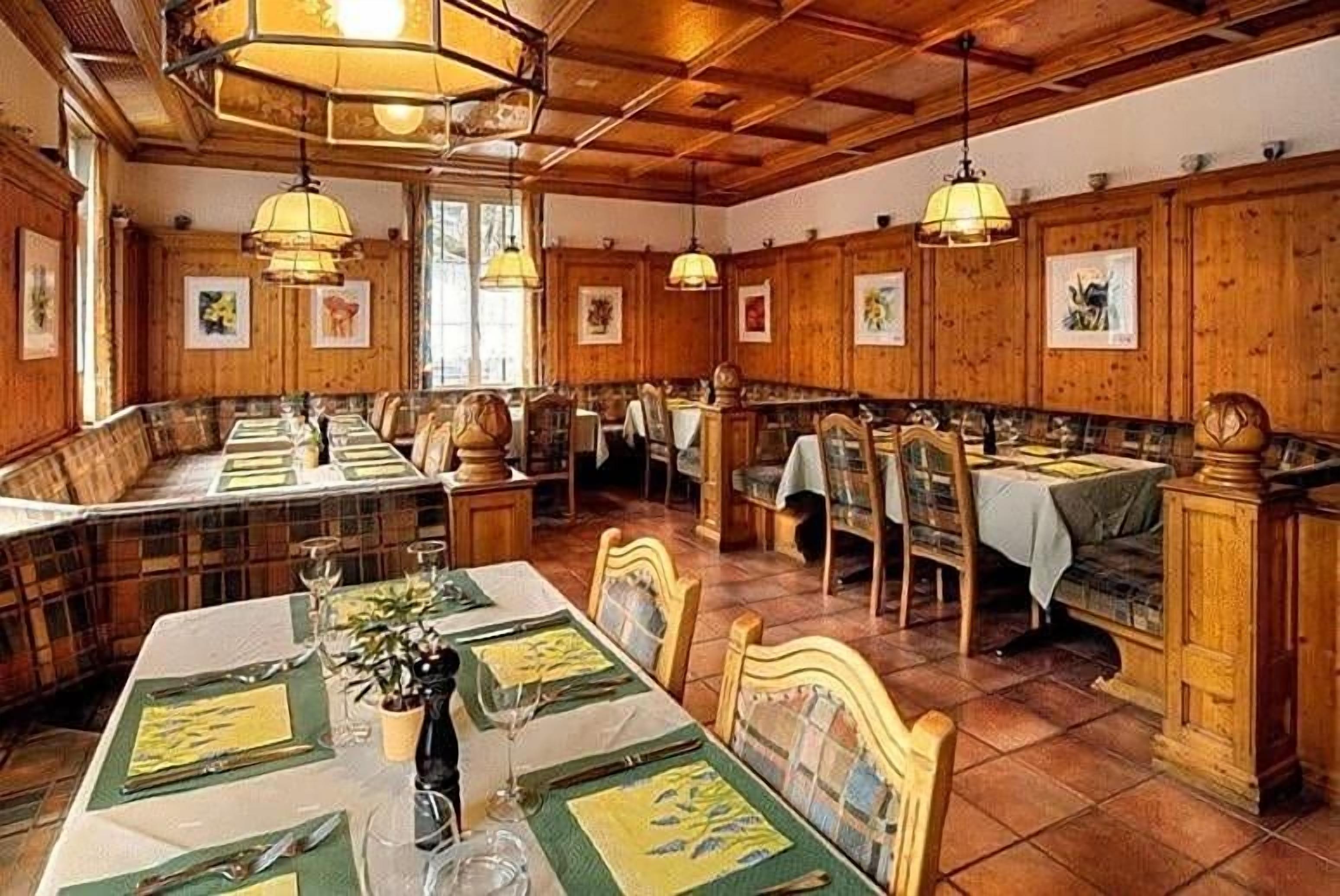 A restaurant with wooden walls, multiple tables, and hanging lamps.
