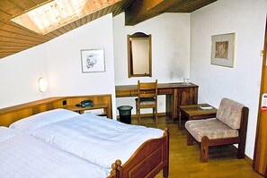 Una habitación con cama, escritorio, silla, sofá, espejo e iluminación en la pared.