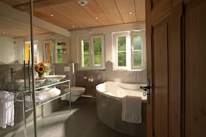 A modern bathroom with a glass shower enclosure, a freestanding bathtub, and a toilet. - Griesalp Hotelzentrum (Reichenbach im Kandertal)