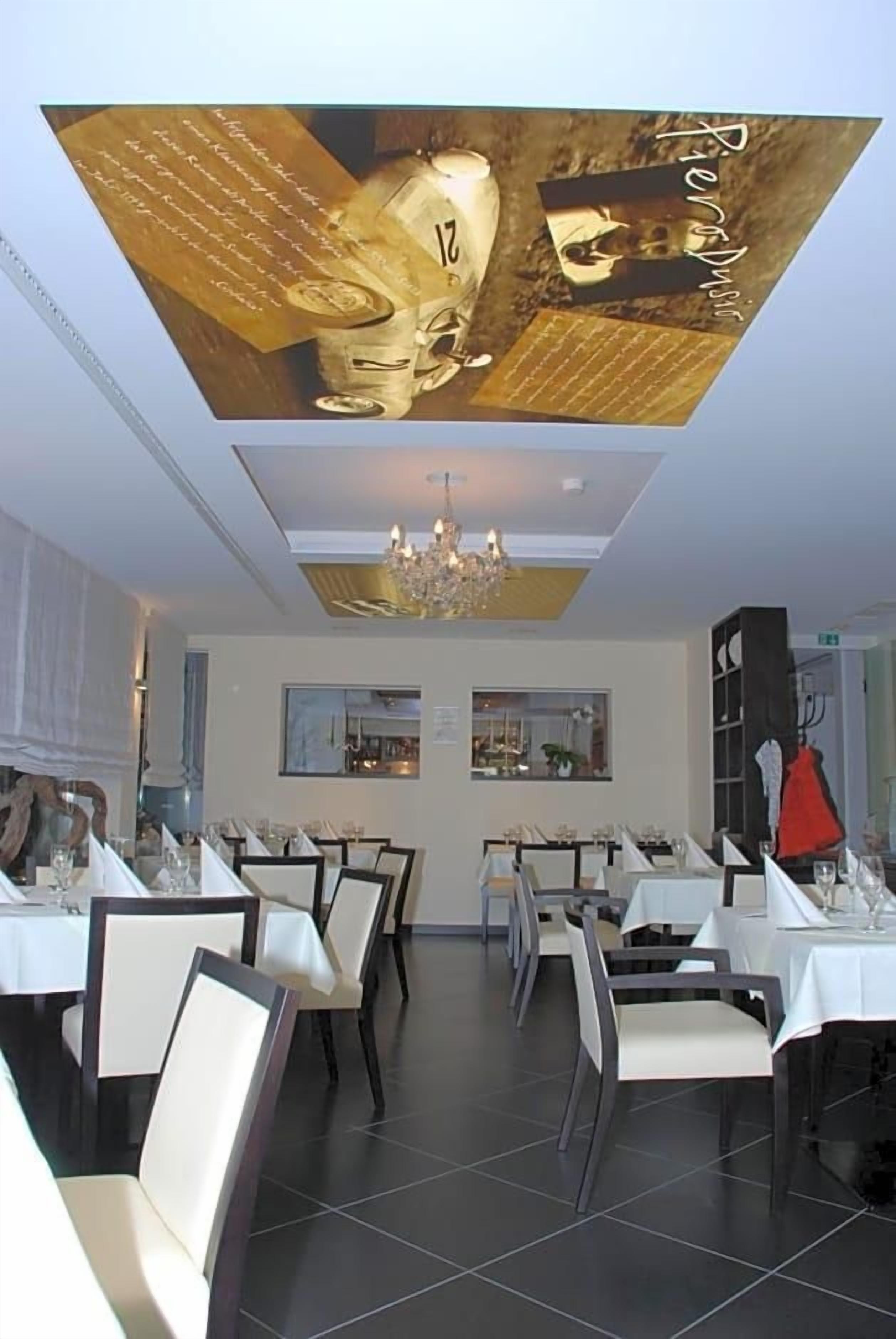 A restaurant with multiple tables, chairs, and a chandelier.