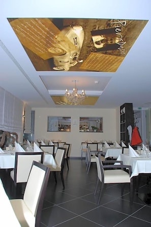 En restaurang med flera bord, stolar och en kristallkrona.
