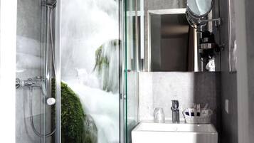 A modern bathroom with a glass-enclosed shower, a sink, and a mirror.