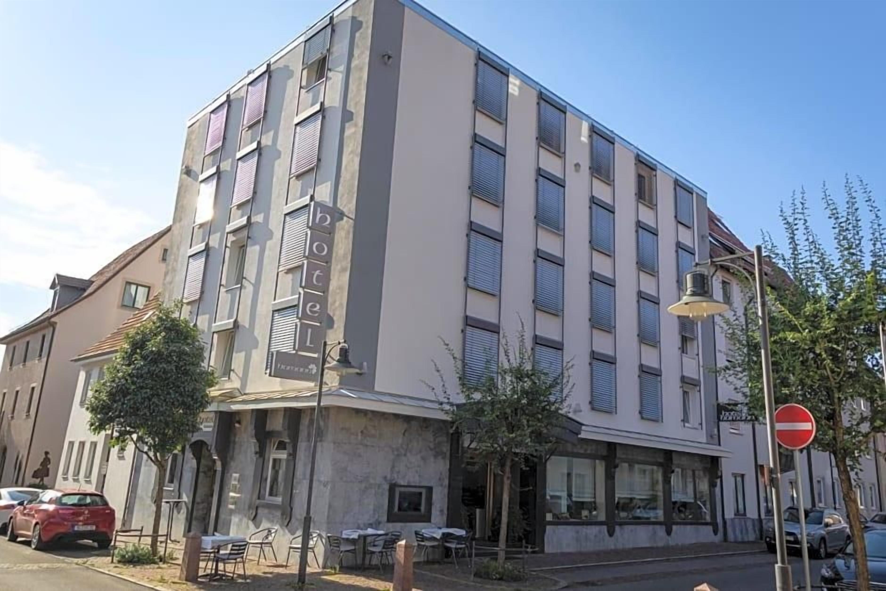 Un hotel de varios pisos con fachada moderna, mobiliario exterior y un letrero de 'prohibido el acceso'.
