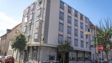 A multi-story hotel with a modern facade, outdoor seating, and a no-entry sign visible.