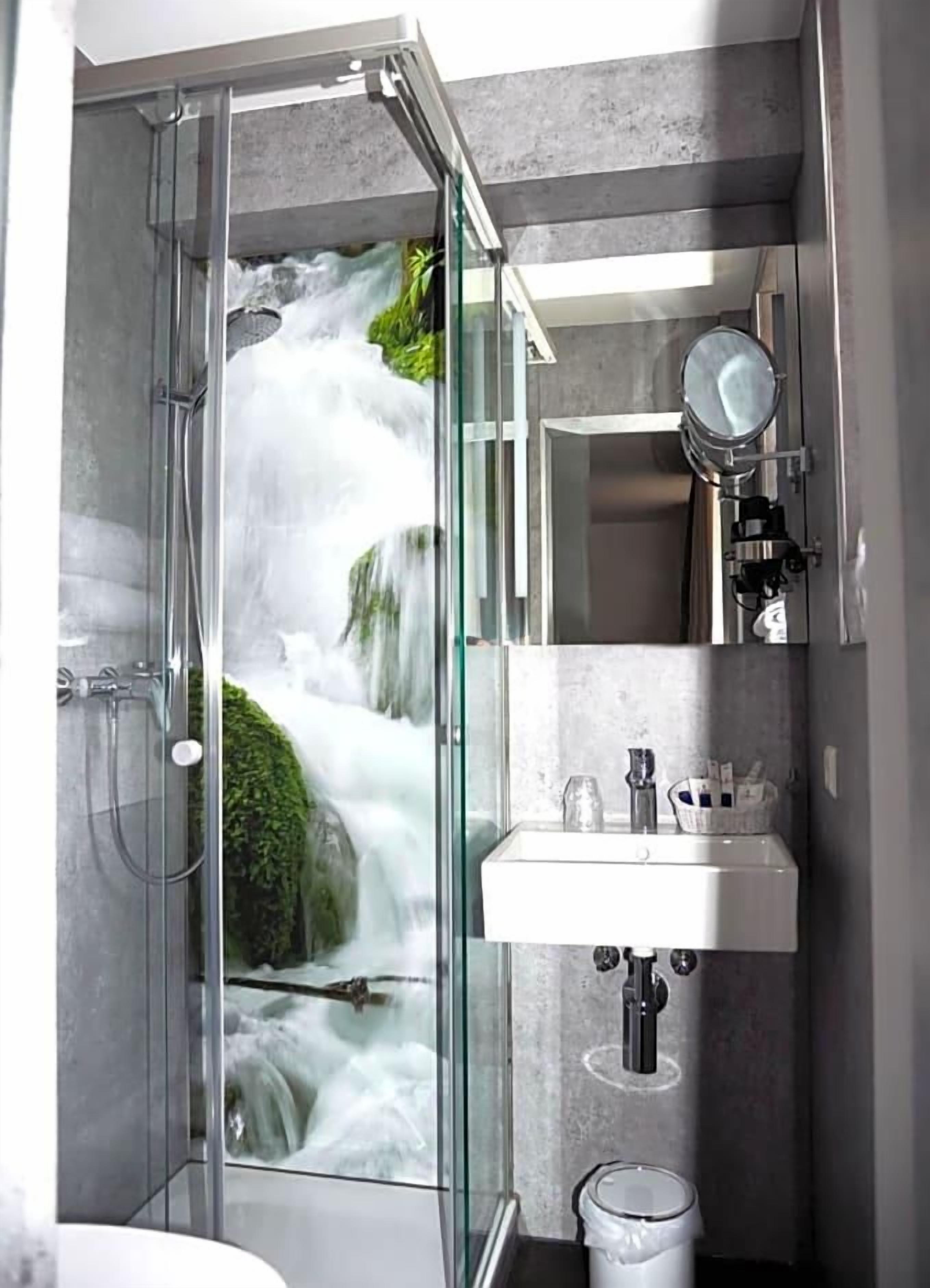 A modern bathroom with a glass-enclosed shower, a sink, and a mirror.