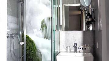A modern bathroom with a glass-enclosed shower, a sink, and a mirror.